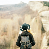 women in hat and backpack staring out at scenery